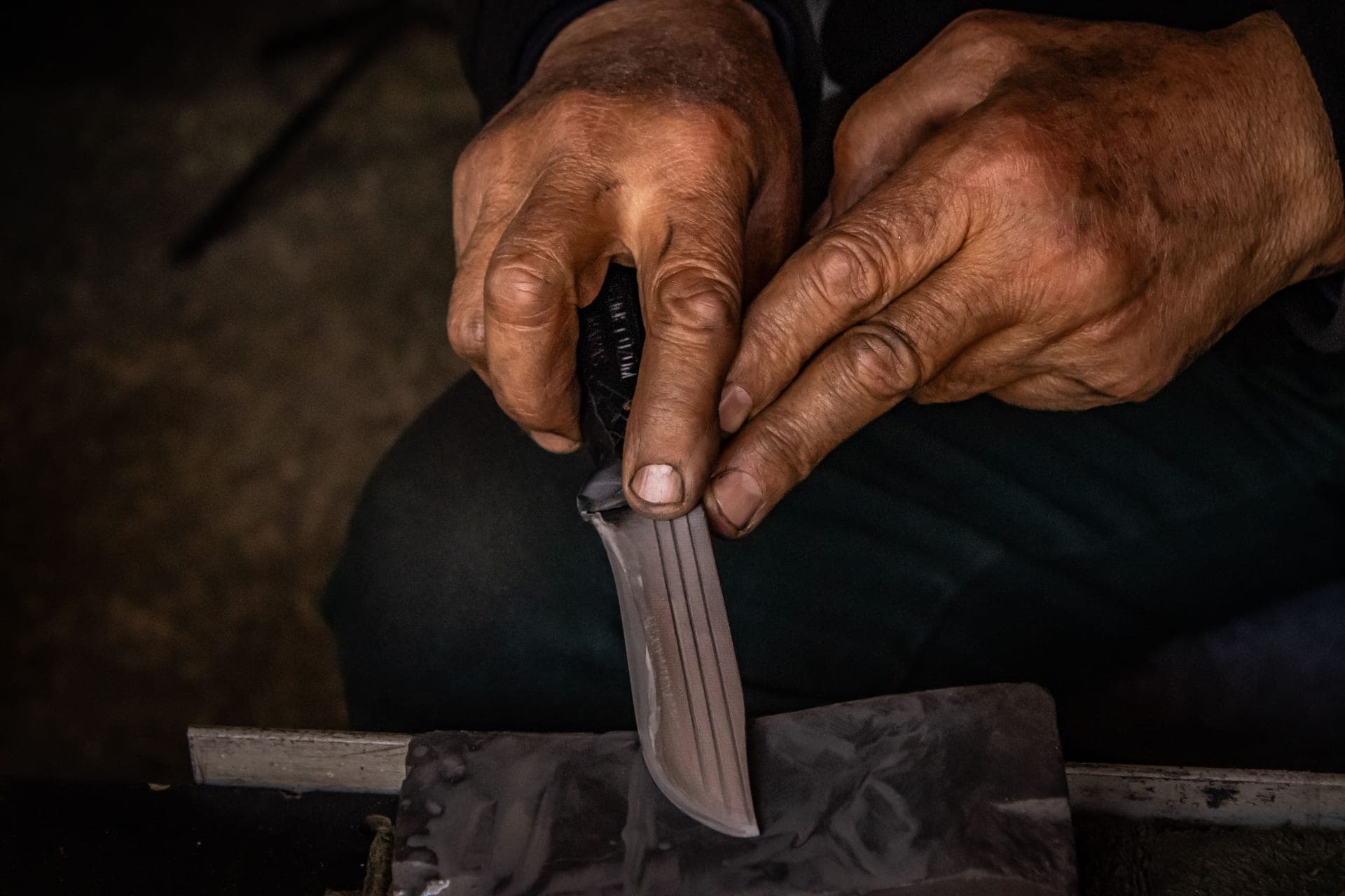 A kitchen knife being sharpened on a wet whetstone